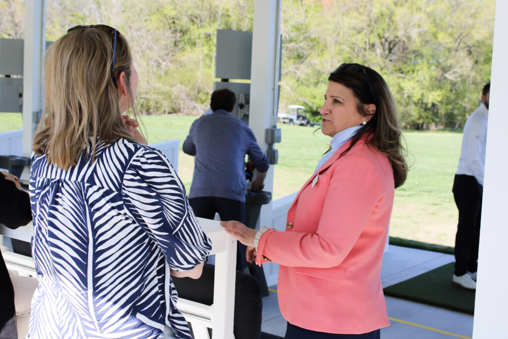 two women have a conversation at the toptracer driving range at queenstown harbor