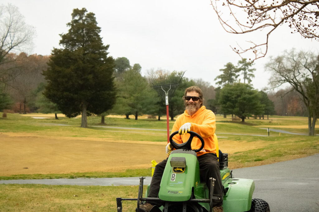 a groundkeeper smiles at queenstown harbor golf resort