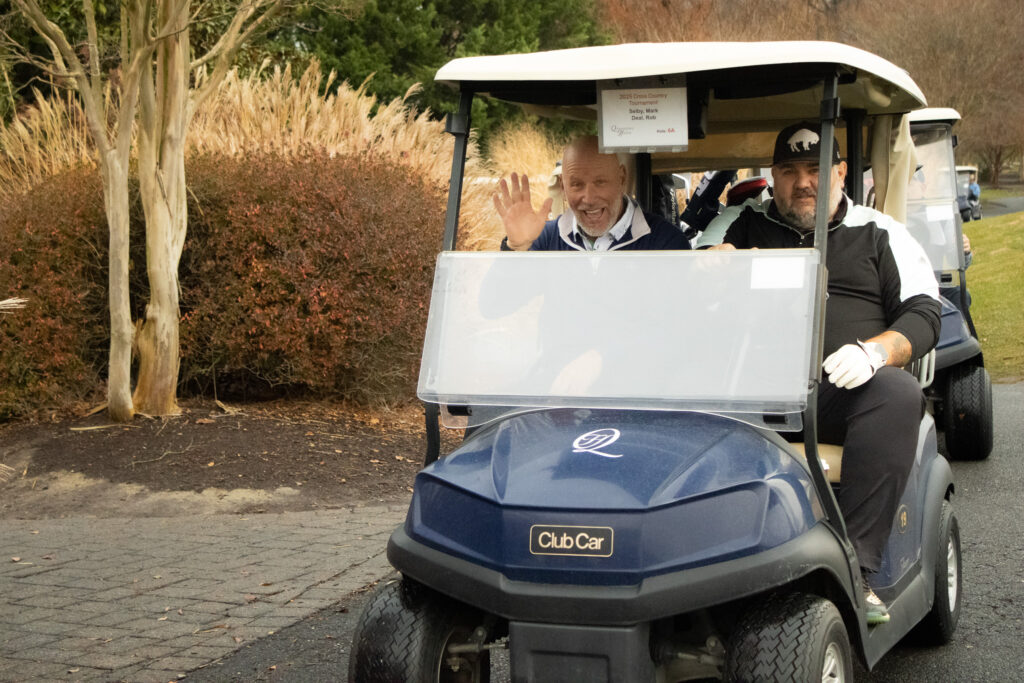 a man waves hello on a golf cart at queenstown harbor