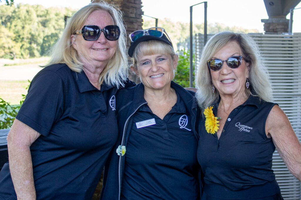 three women stand together and smile at queenstown harbor golf resort